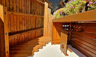 A beautiful balcony with wooden cladding and a table. Colorful flowers adorn the side of the balcony.