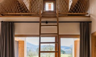 A cozy, modern wooden house with an interior staircase to an attic. Large windows provide a view of nature and ensure plenty of daylight.
