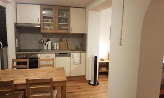 A modern kitchen with a wooden dining table and chairs. There are numerous kitchen appliances and a bright, inviting atmosphere.