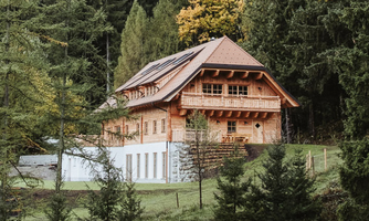 A charming wooden house surrounded by trees and green landscape. The architecture gives the building a cozy atmosphere.