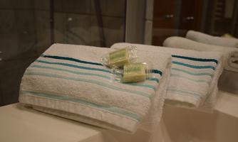 Clean towels with blue stripes are lying on a bathtub. Next to them are small bars of soap.