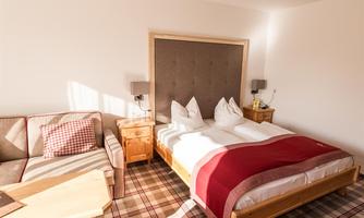 A cozy bedroom with a large bed and a comfortable sofa. The room has a bright, inviting atmosphere.