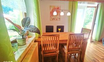 An inviting dining area with a wooden table and chairs. Green and natural tones create a cozy atmosphere.