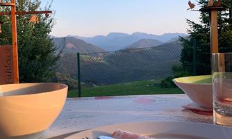 A beautiful view of mountains and valleys at sunset. In the foreground are laid tables with bowls and cutlery.