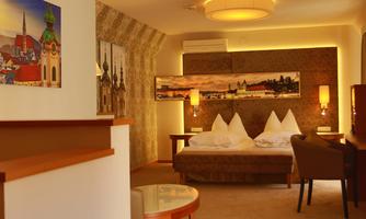 A cozy hotel room with two beds and warm lighting. Cityscape pictures hang on the wall.