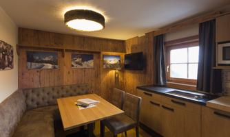 A cozy dining area in a modern kitchen with wooden walls. The table is set for a meal, and the pictures on the wall give the room an inviting atmosphere.