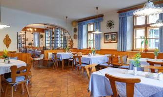 A cozy restaurant with bright tables and blue curtains. The room is friendly designed and inviting.