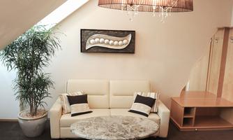 A modern living room with a comfortable white sofa and a round marble table. A decorative artwork hangs on the wall, and a plant adds a fresh accent.