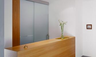A reception desk made of wood with modern elements. On the table stands a vase with green plants.