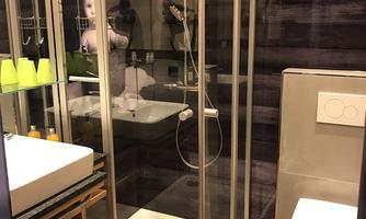 A modern bathroom with a shower cabin and a toilet. The design is stylish with wooden tiles and an elegant shelf.