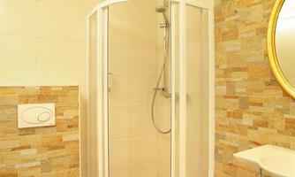 A modern bathroom with a shower cabin and an elegant sink. The walls are designed with tiles in warm colors.
