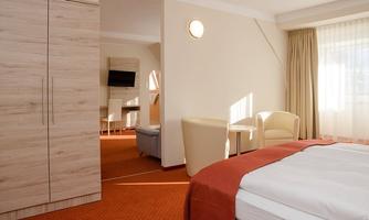 A modern room with a double bed and a cozy seating area. Large windows provide plenty of daylight.