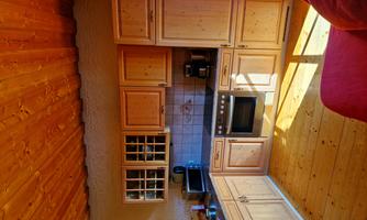 A cozy wooden kitchen with modern appliances. Sunlight streams through the window, creating a warm atmosphere.