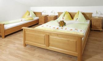 A cozy bedroom with two beds and wooden dressers. The bedding is in soft colors decorated with pillows in yellow and green.