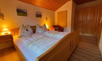 A cozy bedroom with a double bed and wooden decor. Soft light from bedside lamps creates an inviting atmosphere.