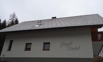 A modern building with a sloping roof and a clear, bright facade. On the wall is the inscription "Siegel Stadel".