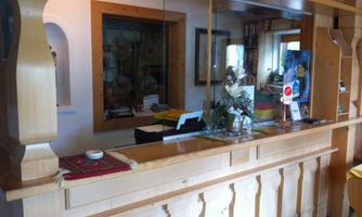A reception desk made of wood with a glass top. On the counter, decorations and informational materials are visible.