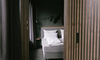 An elegant bedroom with minimalist decor and wooden ceilings. The soft light creates a relaxing atmosphere.