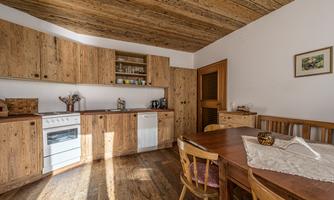 A modern kitchen with wooden cabinets and a large table.  
Lots of daylight enters through the window, creating an inviting atmosphere.