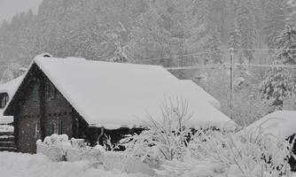 A snowy house in a winter landscape. Fresh snow covers the trees and bushes all around.