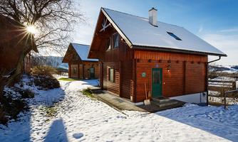 Beautiful wooden facade houses in the snow under a blue sky. The scene radiates tranquility and coziness.