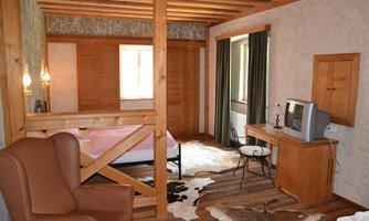 A cozy room with wood paneling and a large window. There is a comfortable sofa, a table, and a television.