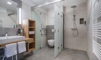 A modern bathroom with a shower, a sink, and a toilet. The walls are light and the decor is minimalist.