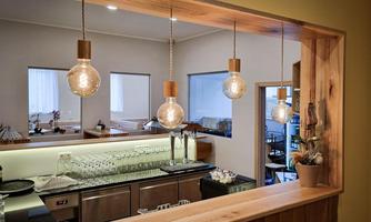 The view of a modern bar with hanging lamps and an elegant bar counter. The atmosphere is cozy and inviting.