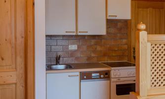 A modern kitchen with white cabinets and a wood panel. The space has a warm, inviting character.