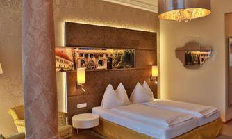 A modern hotel room with a double bed and elegant decor. The room features soft lighting and a stylish wall design.