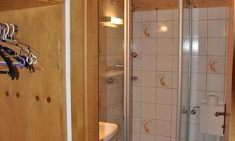 A bathroom with a shower, toilet, and sink. It has bright tiles and wooden details.