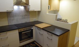 A modern kitchen with a cooking hob, an oven, and a wooden board. The walls are in a light shade, and the decor feels friendly and inviting.