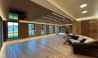 A modern, spacious room with wooden flooring and large windows. The walls are designed with wooden panels and the lighting is pleasant.