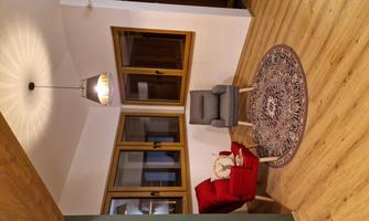 A cozy living area with two armchairs, a rug, and large windows. The room has a modern look with hardwood flooring and warm lighting.