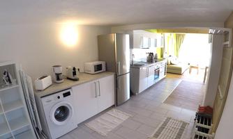 A modern kitchen with white furniture and appliances. It is bright and cheerful, with a window that lets in daylight.