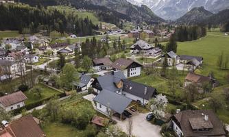 A picturesque village in the mountains with many houses and green meadows. In the background, impressive mountains and a clear landscape can be seen.