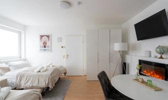 A modern room with two beds, an elegant table, and a television. The soft lighting creates an inviting atmosphere.
