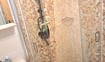 A modern shower with glass walls and stone tiles. The space is bright and clean, with clear lines.