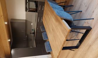 Modern kitchen with a large wooden table and blue chairs. The furniture is in a simple gray tone and provides an inviting atmosphere.