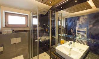 A modern bathroom with a glass shower and an elegant sink. The walls are decorated with stylish accents.