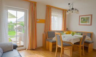 A cozy dining area with a round table and chairs. Large windows let in plenty of light and offer a view of the garden.