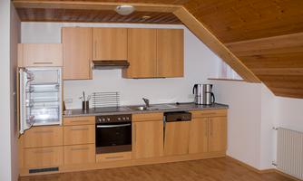 A modern kitchen with wooden cabinets and a stainless steel sink. The amenities include a refrigerator, a stove, and a microwave.