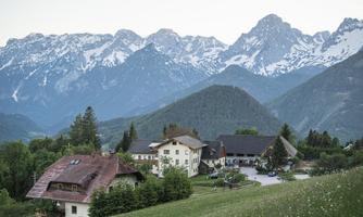 A picturesque village in the Alps, surrounded by majestic mountains. The landscape is green and peaceful, perfect for relaxation in nature.
