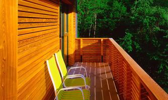 A balcony with wooden cladding and two colorful chairs. In the background, green trees are visible.
