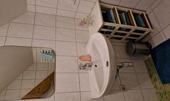 A modern small bathroom with white tiles and a sink. On a shelf, blue towels and a blooming plant are placed.