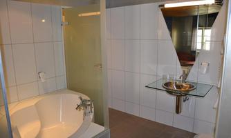 A modern bathroom with a bathtub and a shower cubicle. It has bright tiles and a simple sink.