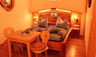 A cozy room with a large bed and traditional pillows. A wooden table and chairs complete the rustic atmosphere.