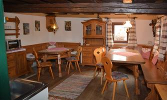 A cozy room with wooden furniture and a rustic ambiance. The space features a large table, chairs, and decorative elements on the walls.
