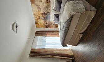 A modern bedroom with a large bed and stylish furniture. The wall is decorated with a beautiful leaf pattern, and the light is friendly and inviting.