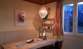 A cozy dining area with a wooden table and black chairs. Large windows offer a view of the mountains and let in plenty of light.